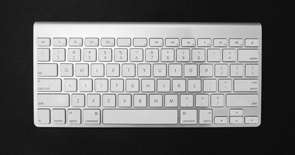 An apple keyboard on a black background, symbolizing the process of developing your college essay.