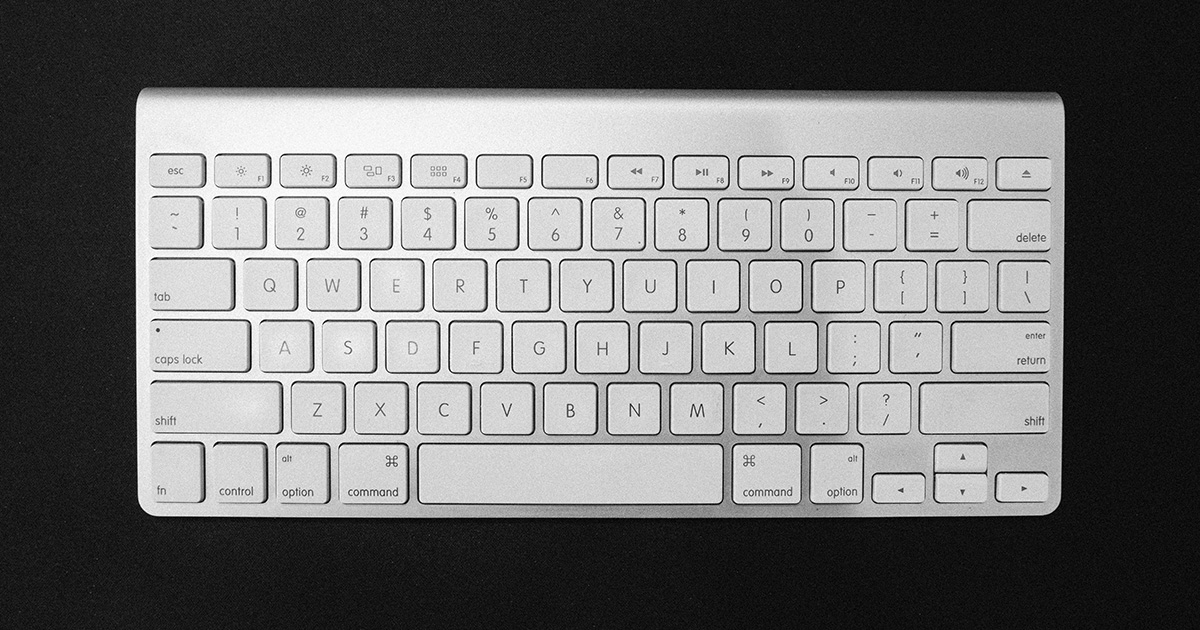 An apple keyboard on a black background, symbolizing the process of developing your college essay.