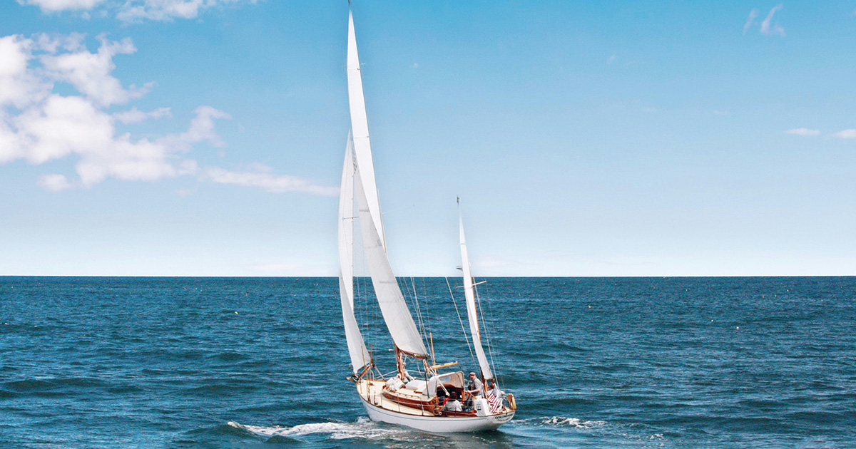 A white sail boat sailing in a blue ocean with a blue sky in the background. It symbolizes EFSC SAIL Services.