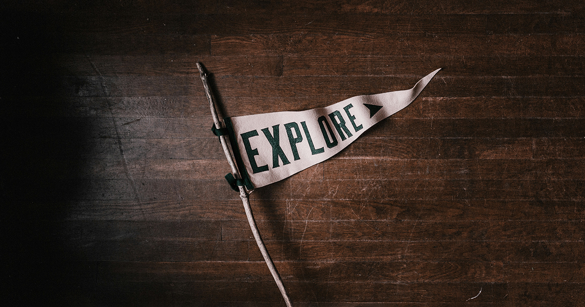 A triangular flag that has "explore" written on it attached to a stick. The image represents exploring your college campus.