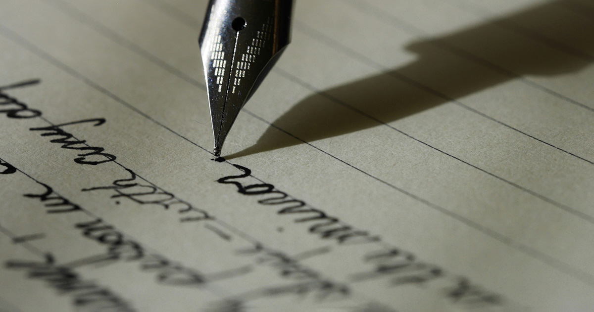 A black fountain pen writing in cursive on a black lined notebook. The image creates ideas about how to kick-start your writing career.