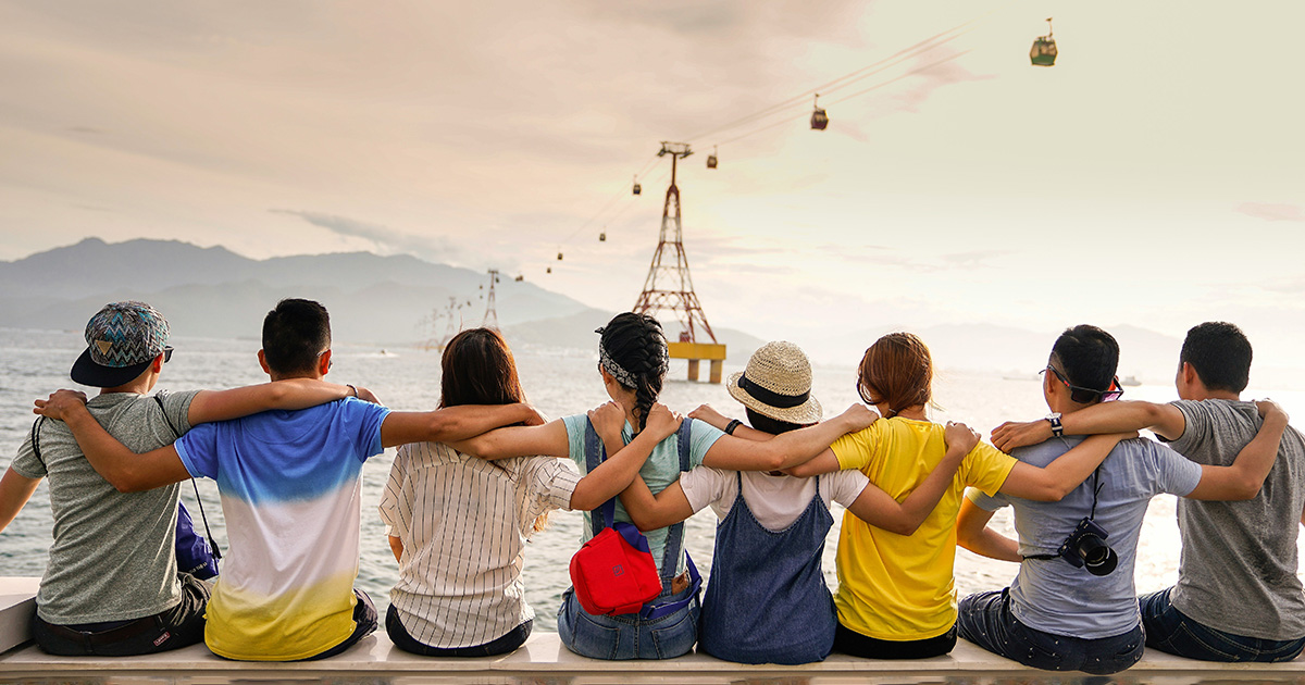 A diverse group of friends with their arms around each other looking at a gondola over the sea. This image represents the importance of making connections in college.