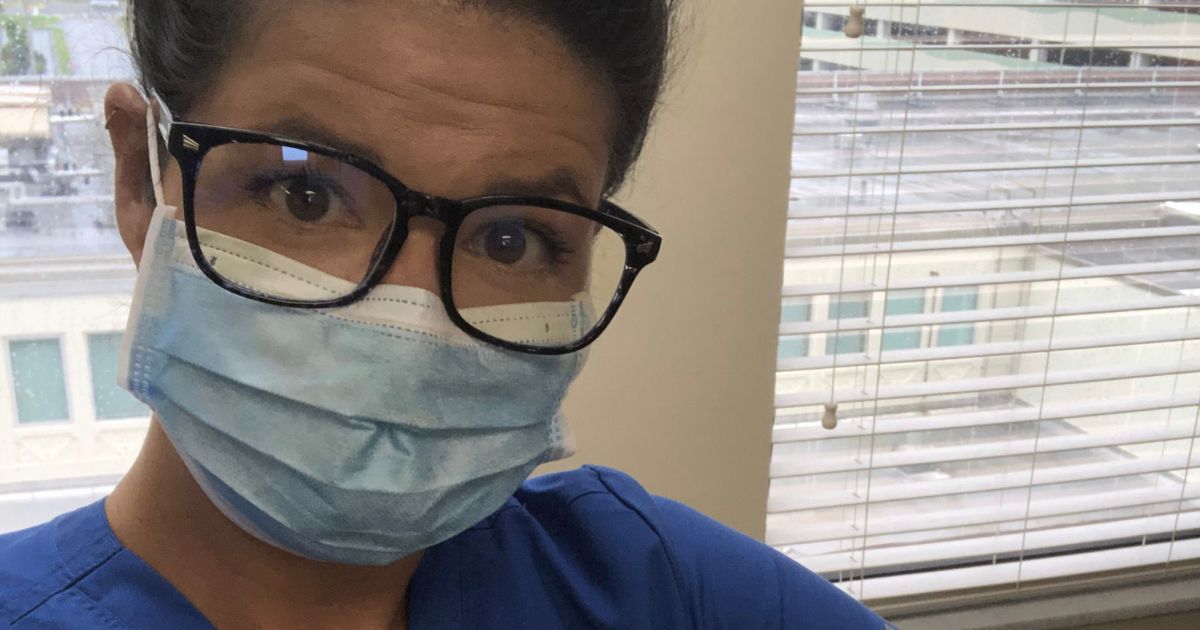 A woman with dark glasses and dark hair pulled into a bun (Spenser Streml, overcoming college setbacks) wearing blue scrubs and a face mask.