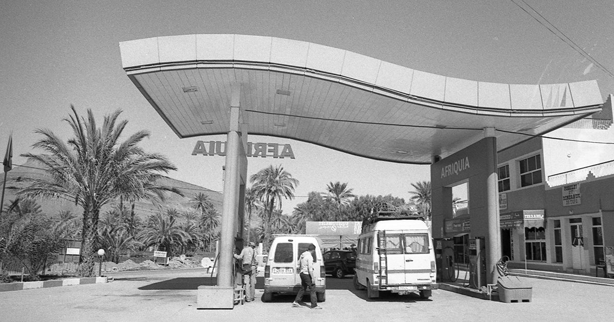 Two people filling up their vehicles at a Moroccan gas station named Afriquia. This image is an example of why students should take photography classes.
