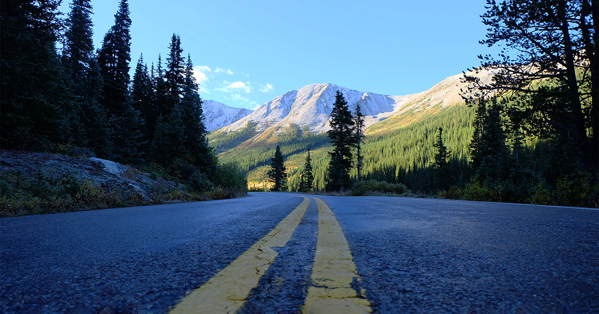 A curvy road with mountains in the background, symbolizing the long road through life and the value of mentorship.