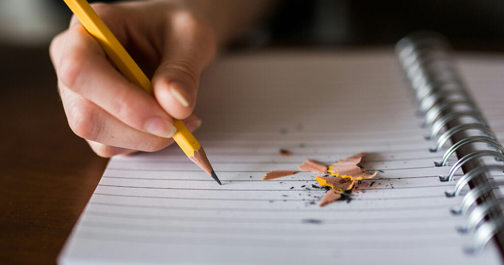 Person writing in a notebook, symbolizing your first college class.