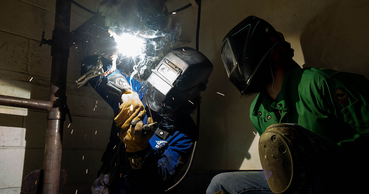 Two people in protective gear weld a metal object in EFSC's non-credit welding course.