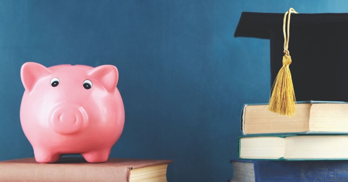 Paying for college: a piggy bank on top of a book and a grad cap on top of three books.