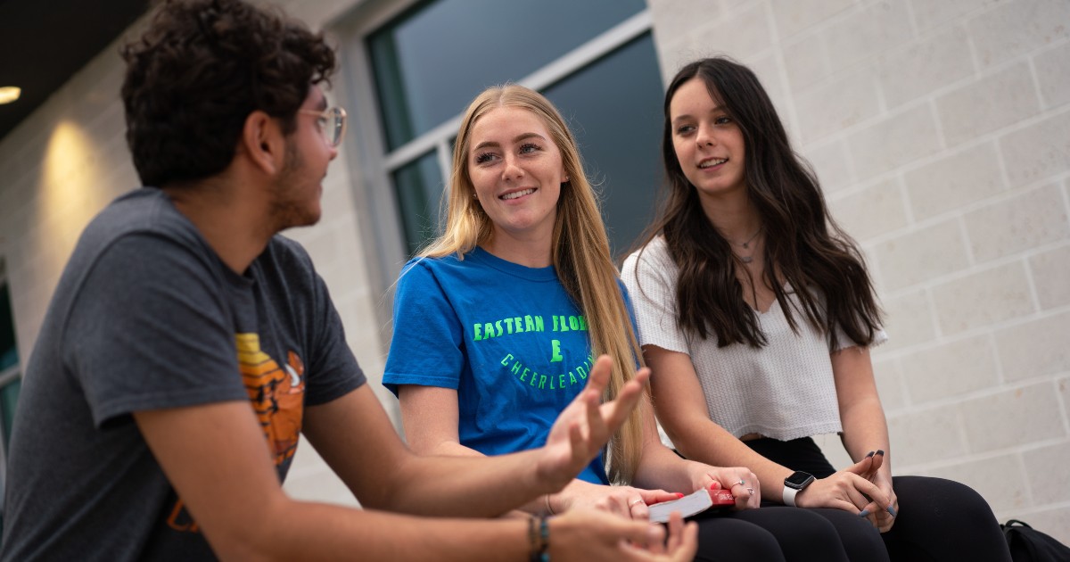 Three students sitting and talking together, practicing good soft skills.