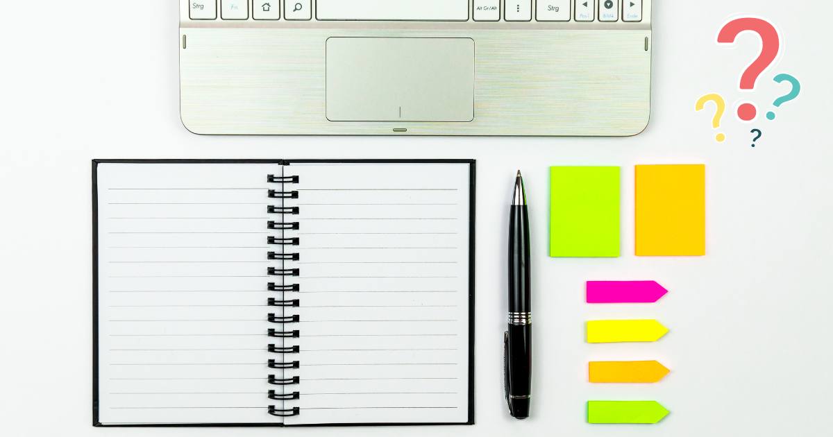 A notebook, pen, sticky notes, file tabs, and a laptop tastefully arranged on a white desk. This is a good example of an organizational style.