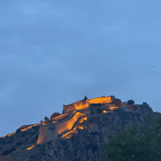 A Greek acropolis atop a mountain lit by the setting sun