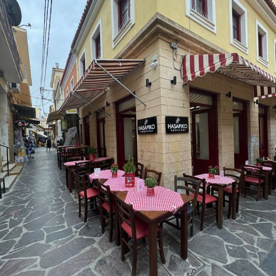 A view down a stone street with pink tables and outdoor dining under an awning