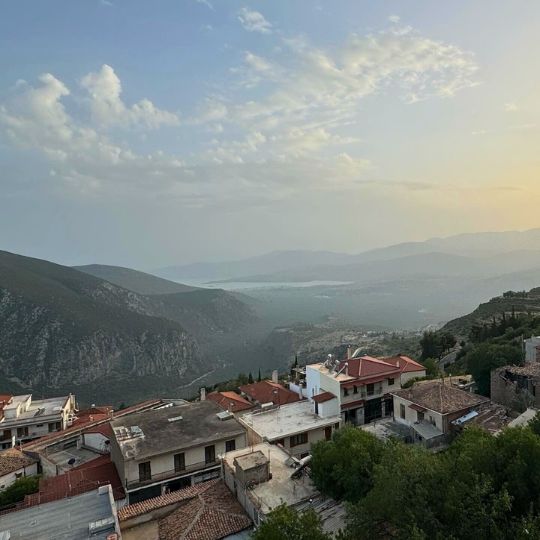 A view of the Greek villas from a mountaintop as the sun rises over the misty horizon