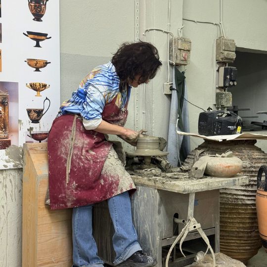 A pottery maker works with clay in a shop