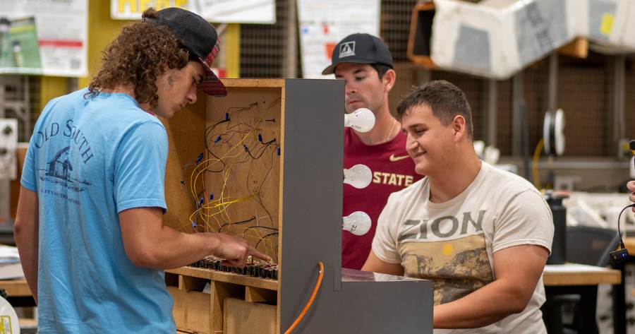 A group of young HVAC students in EFSC's HVAC program learning on a circuit board together