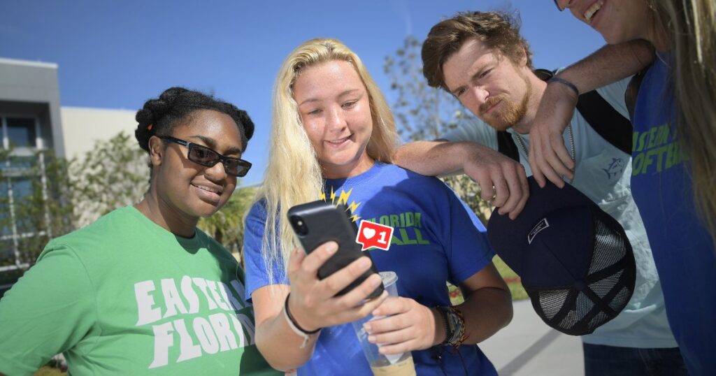 A group of EFSC students gather around a cellphone to look at what's on social media and use social media.