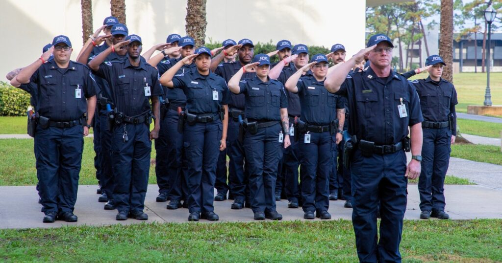 Group of diverse law enforcement officers and trainer saluting together
