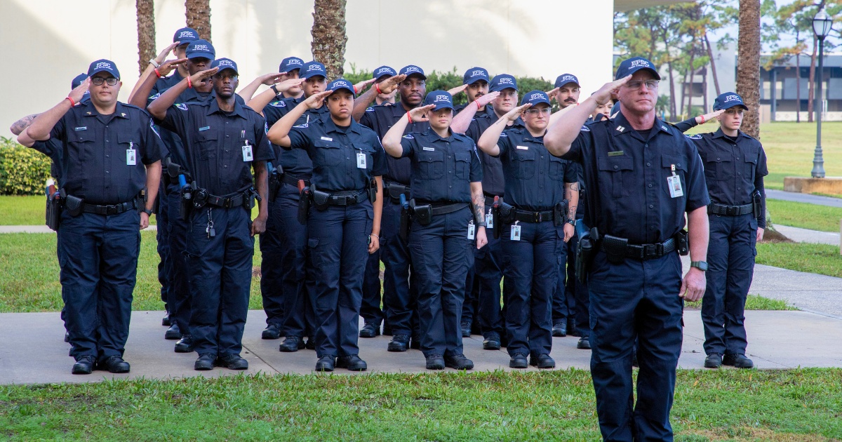 Group of diverse law enforcement officers and trainer saluting together