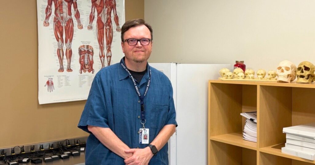Justin Archey, EFSC Crime Scene Technology instructor, stands by a shelf of human skull replicas