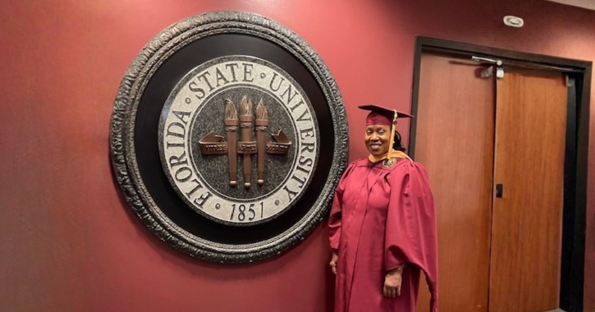 Shelleyann Romain standing in graduation regalia next to the Florida State University Seal